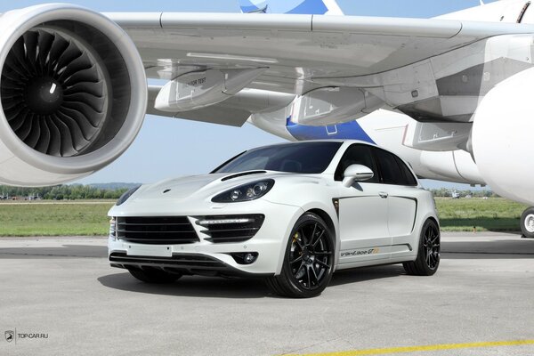 Coche blanco bajo el ala del avión