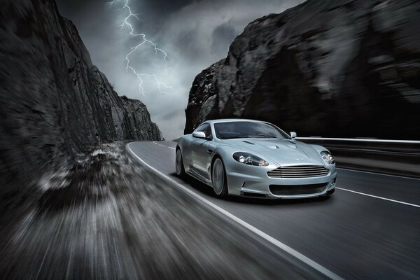 A gray car rushes along a mountain road