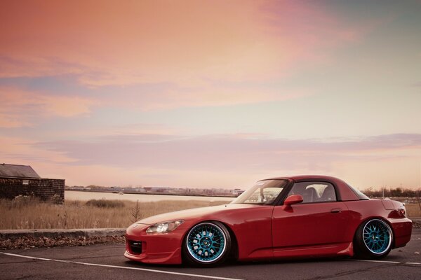 Photo of a beautiful red car on the background of the sunset sky