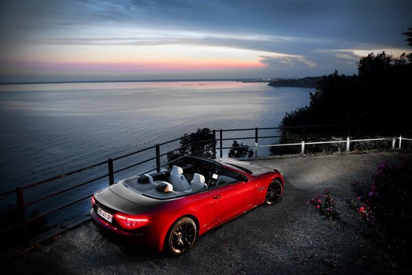 Car with an open top in red color on the view of the sea