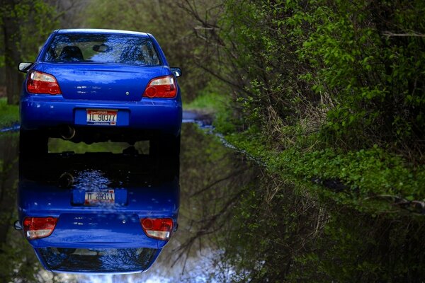 Auto blu sulla strada bagnata