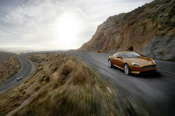 A brown car rushes along a mountain serpentine