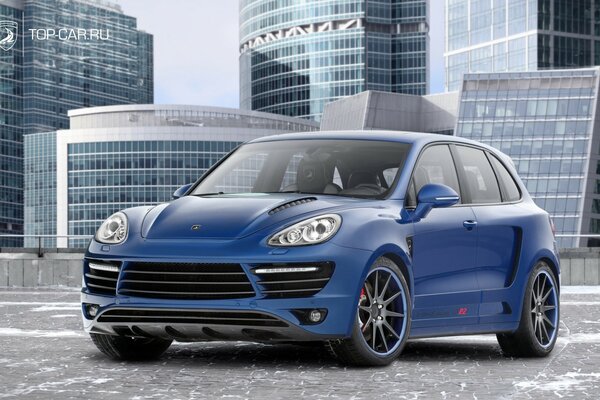 A blue car stands on gray asphalt against the background of high-rise buildings