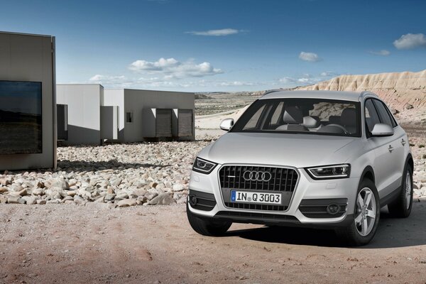 A silver car stands against the background of mountains and rocks