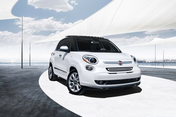 A small white car stands against the background of water