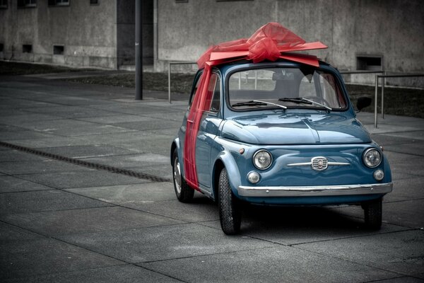 A small blue car with a gift bow