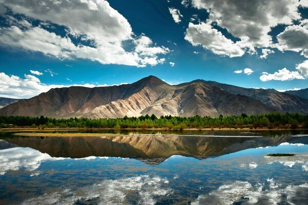 पहाड़ों और पानी की सतह पर सफेद चलने वाले बादल
