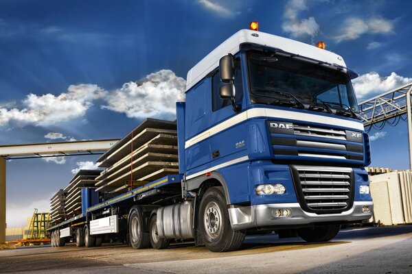 A heavy truck is carrying planks from a warehouse