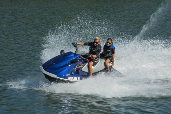 Dos personas montan una moto de agua azul