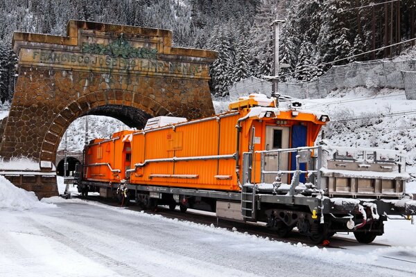 Eine orangefarbene Lokomotive fährt durch einen Bogen