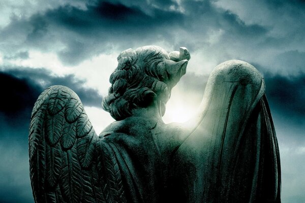 Angel statue with wings on the background of clouds