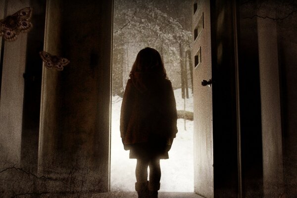 The lonely figure of a girl on the background of an open door