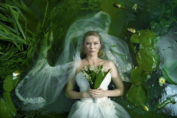 Braut mit einem Blumenstrauß aus Maiglöckchen im weißen Kleid