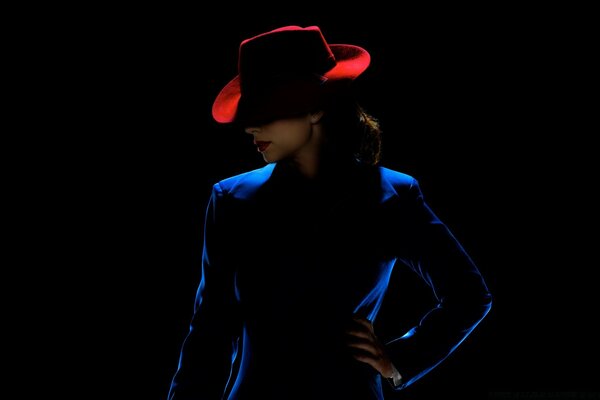 Slender girl in a blue suit and with a red hat