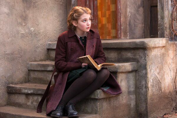 A girl with a retro hairstyle in a coat on the stairs