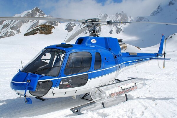 Helicóptero azul em cima de uma montanha de neve