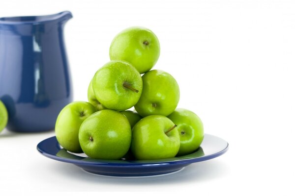 Green apples on a plate and a teapot