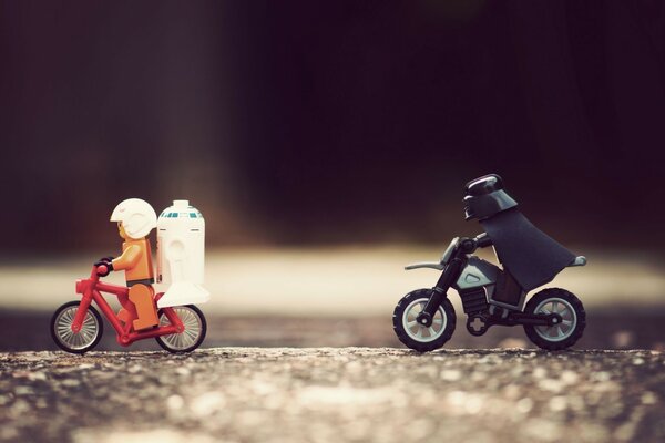 Two little men riding motorcycles on the road