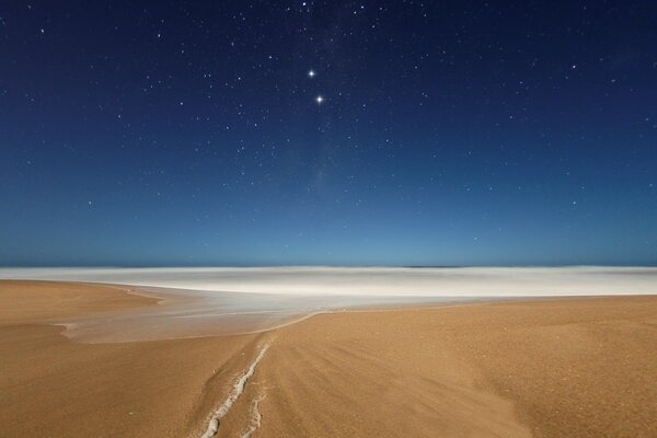 Cielo estrellado sobre el mar y la arena