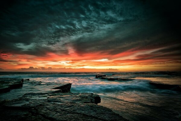 Puesta de sol sombría en la costa rocosa