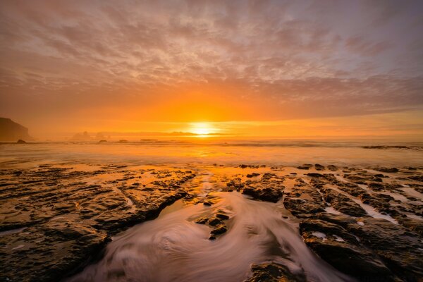 Ao pôr do sol, o mar se funde com as nuvens de ar