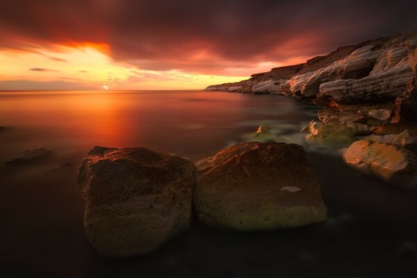 Beau coucher de soleil sur la mer et les pierres sont grandes