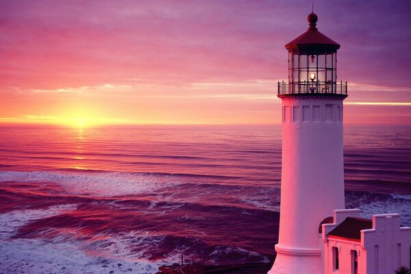 Faro en el fondo de los rayos púrpuras de la puesta de sol