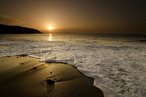 Mousse de mer sur la plage de sable et coucher de soleil