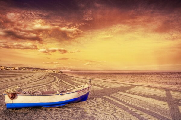 Coucher de soleil inhabituel. Bateau sur le sable