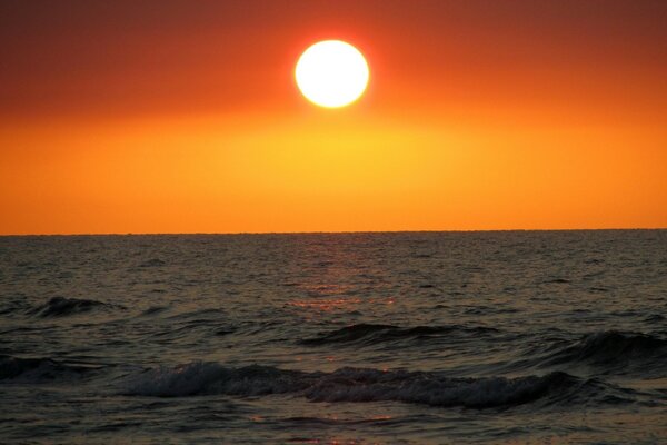 El sol se pone en el mar sobre un fondo rojo-naranja