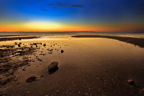 The beach sand merges with the orange mountains.