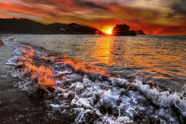 Tramonto rosso sulla spiaggia vicino al mare