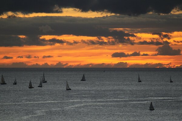 Barcos en el océano en medio de la puesta del sol