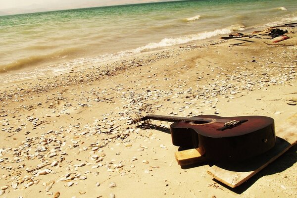 E alguém esqueceu a guitarra no mar na areia