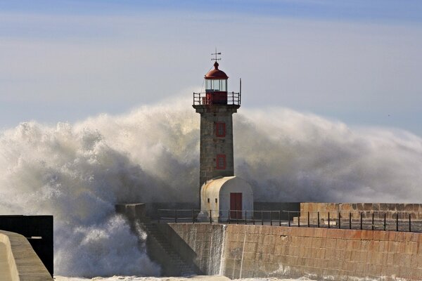 A huge wave crashing into the current of the lighthouse