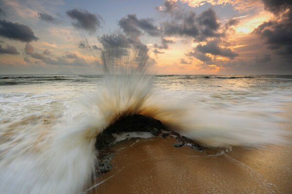 Sonnenuntergang. Sandstrand und Schaumwellen