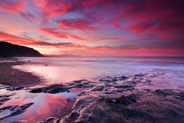 Cielo carmesí y costa de piedra del mar