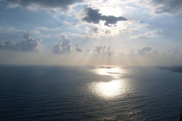 El sol a través de las nubes se comunica con el mar