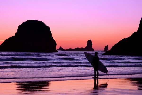 Surfista en el fondo del cielo carmesí y el mar