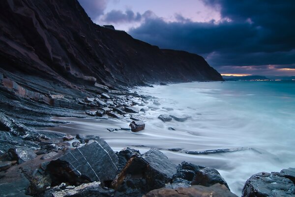 Les vagues de mousse battent sur la falaise de la mer