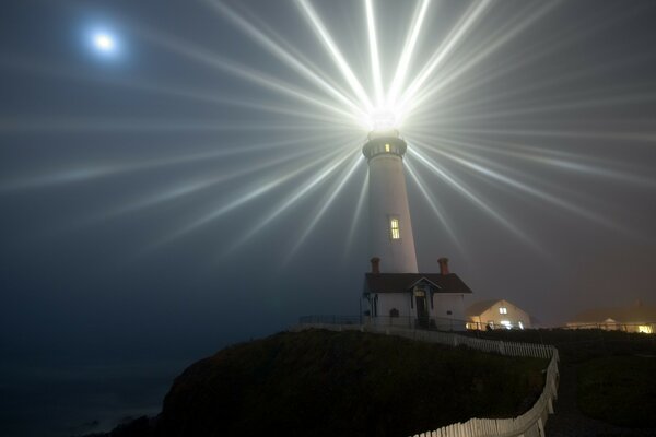 The lighthouse illuminates the entire starry sky