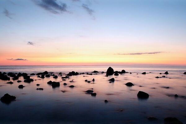 Large rocks stick out of the seawater at sunset