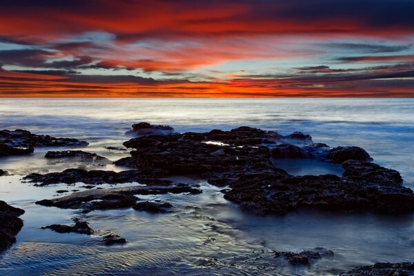 The cold sea dawn illuminates the huge rocks near the shore