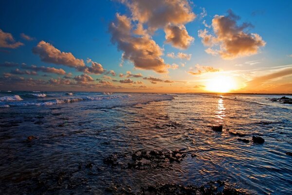 La puesta de sol dorada se refleja en el agua de mar