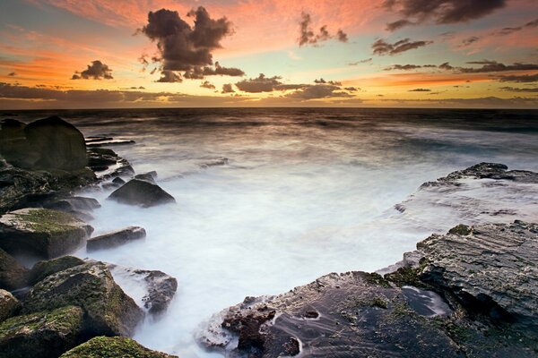 Belo pôr do sol na costa rochosa do mar