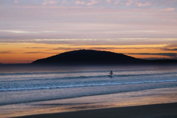 Lonely surfer in the sea at sunset