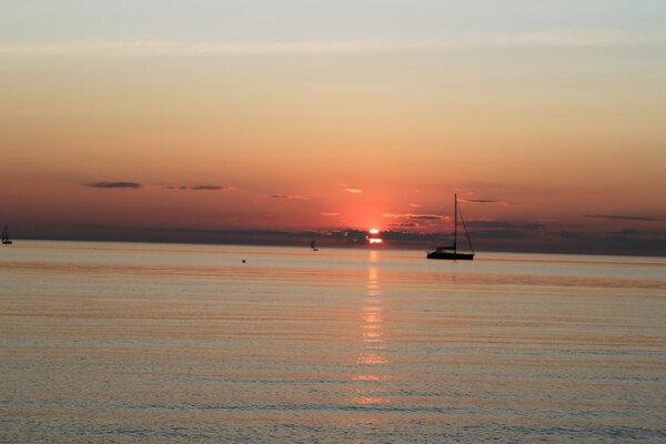 Barcos en la superficie del mar a la luz del sol Poniente