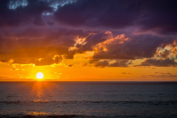 The sun is setting at the edge of the Pacific Ocean