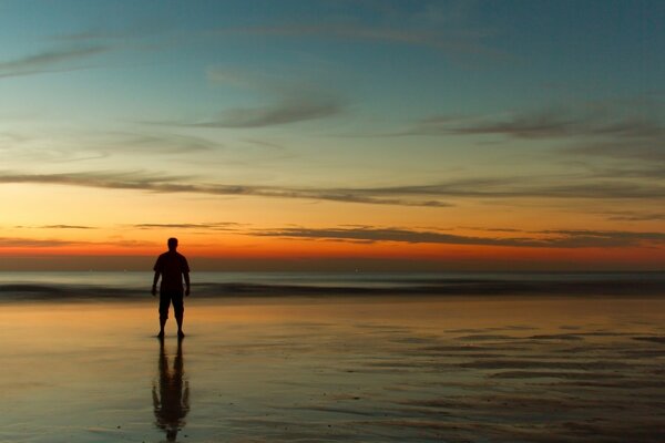 Uomo in riva al mare al tramonto