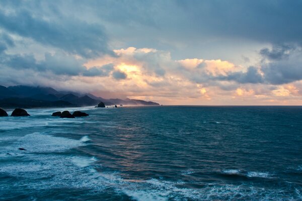 Thunderclouds over the sea in bad weather, waves with foam break on coastal rocks